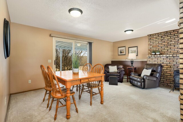 dining room with light carpet, a textured ceiling, and baseboards