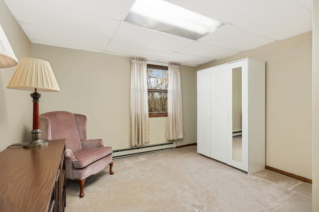 living area with baseboard heating, carpet flooring, a drop ceiling, a baseboard radiator, and baseboards