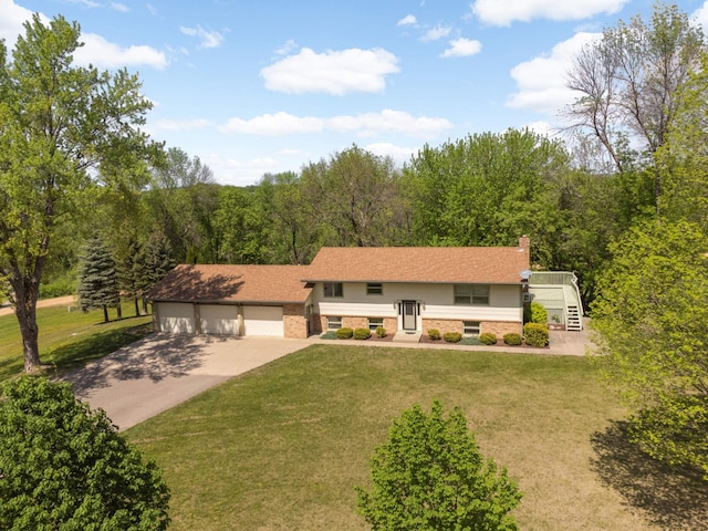 raised ranch featuring driveway, brick siding, a front yard, and a chimney