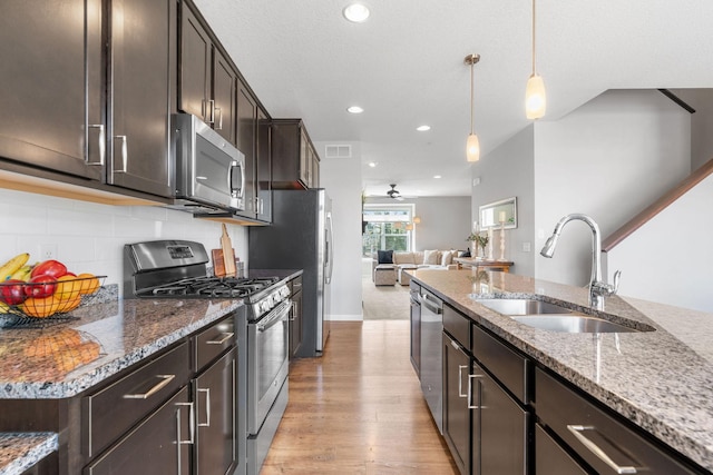 8945 Village Loop, Chanhassen, MN 55317 - kitchen featuring stainless steel appliances, a sink, light wood-type flooring, dark brown cabinets, and stone countertops