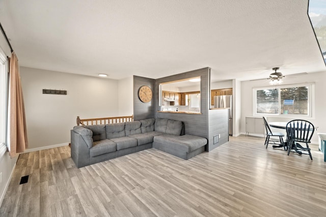 2510 152nd Ln NE, Ham Lake, MN 55304 - living room featuring visible vents, baseboards, light wood-type flooring, a textured ceiling, and a ceiling fan