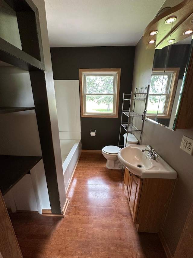 10855 150th St NE, Spicer, MN 56288 - full bath featuring toilet, a bathtub, vanity, wood finished floors, and baseboards