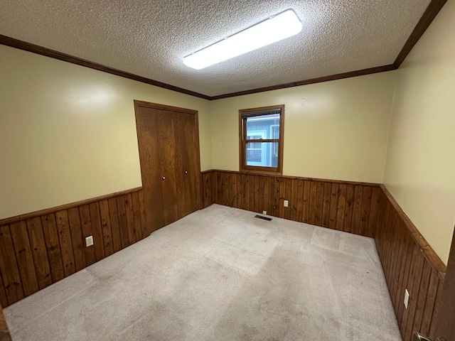 6480 Long Lake Rd, Willmar, MN 56201 - unfurnished room with a wainscoted wall, wood walls, a textured ceiling, carpet floors, and ornamental molding