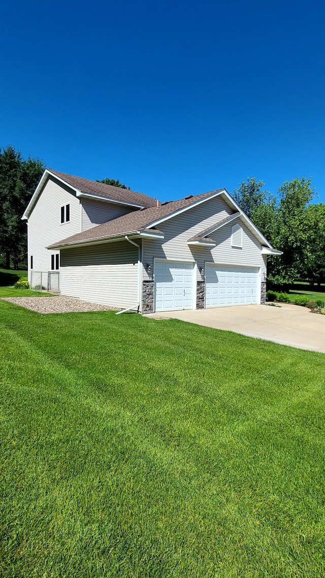 1404 19th Ave NW, Faribault, MN 55021 - view of side of home with a yard, a garage, driveway, and stone siding