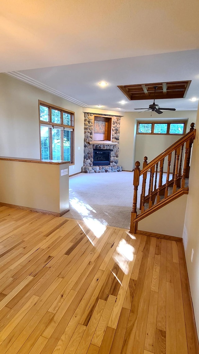 1404 19th Ave NW, Faribault, MN 55021 - unfurnished living room featuring light wood finished floors, a fireplace, ornamental molding, and a ceiling fan