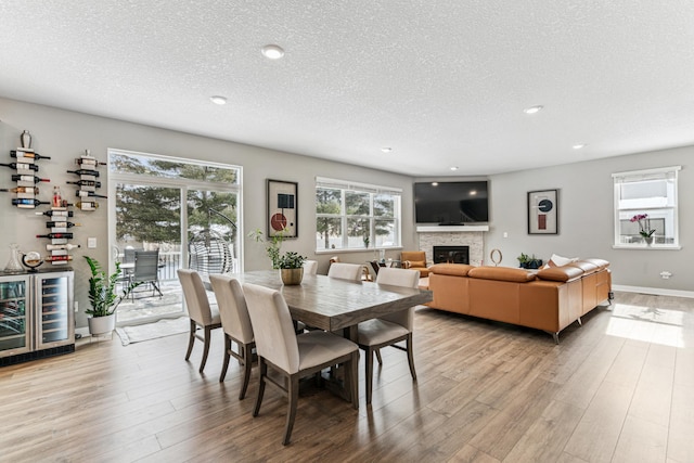 12972 Bauer Dr N, Champlin, MN 55316 - dining room with wine cooler, a textured ceiling, a fireplace, light wood finished floors, and recessed lighting