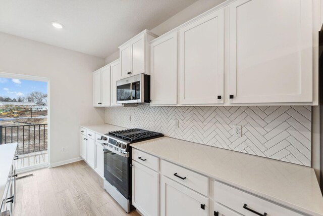 1537 Traverse Ln W, Saint Paul, MN 55118 - kitchen with stainless steel microwave, gas range oven, decorative backsplash, light countertops, and white cabinetry