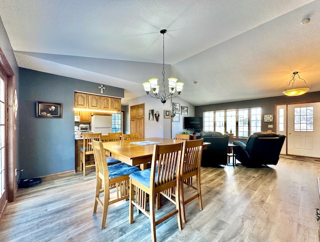 dining area with a chandelier, baseboards, vaulted ceiling, and light wood-style floors