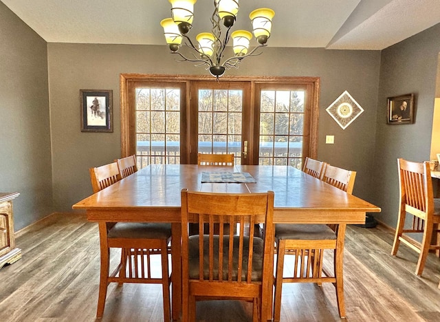 dining space with baseboards, an inviting chandelier, and wood finished floors