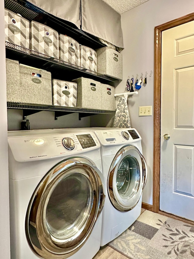 clothes washing area with laundry area, baseboards, and washing machine and dryer