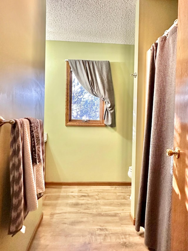 bathroom with baseboards, a textured ceiling, and wood finished floors