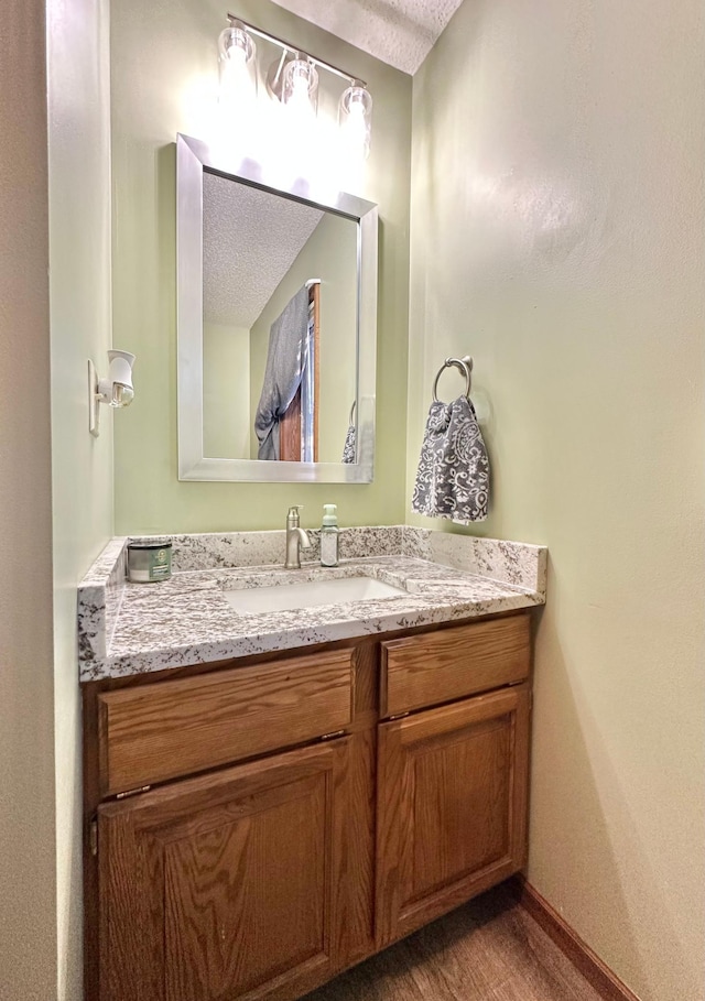 bathroom with vanity, baseboards, and a textured ceiling