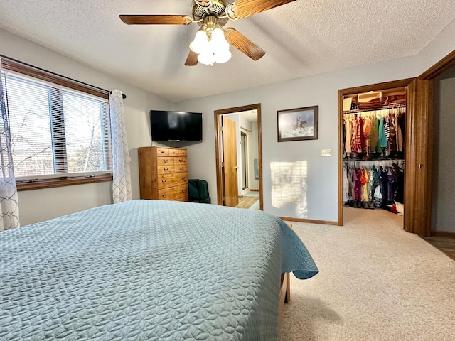 carpeted bedroom featuring a closet, a textured ceiling, baseboards, and ceiling fan