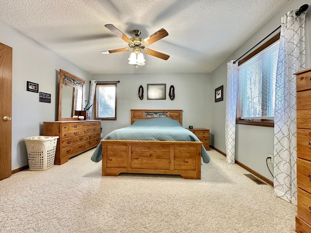 carpeted bedroom featuring a ceiling fan, a textured ceiling, visible vents, and baseboards