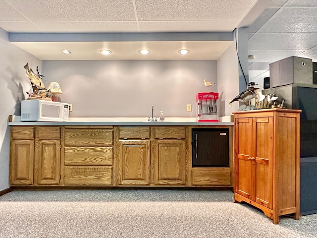 bar featuring wet bar, light colored carpet, a paneled ceiling, and white microwave