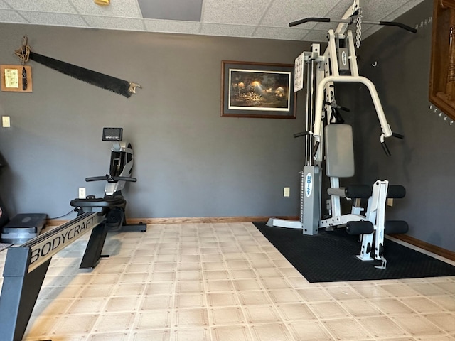 workout area featuring baseboards and a drop ceiling