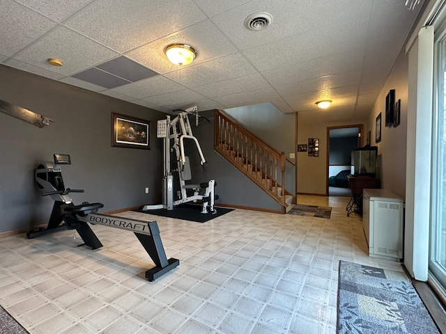 workout area featuring baseboards, visible vents, and a paneled ceiling