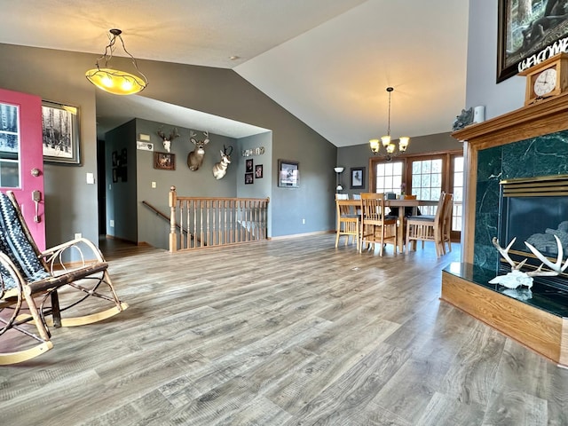 living room featuring vaulted ceiling, wood finished floors, and a notable chandelier