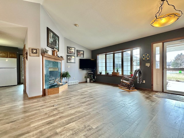 living room featuring visible vents, light wood-style floors, vaulted ceiling, and a wealth of natural light