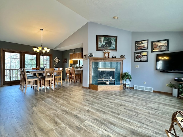 living room featuring visible vents, an inviting chandelier, wood finished floors, a fireplace, and baseboards