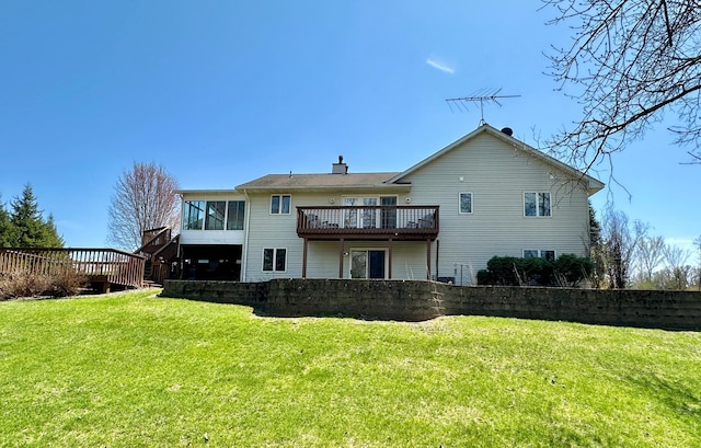 rear view of property featuring a yard, a wooden deck, a sunroom, and a chimney