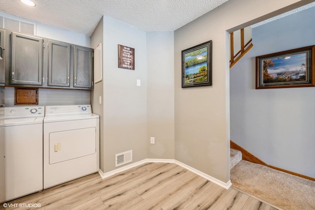 3040 Shields Dr Unit 102, Eagan, MN 55121 - laundry area featuring cabinet space, independent washer and dryer, light wood-style flooring, baseboards, and a textured ceiling