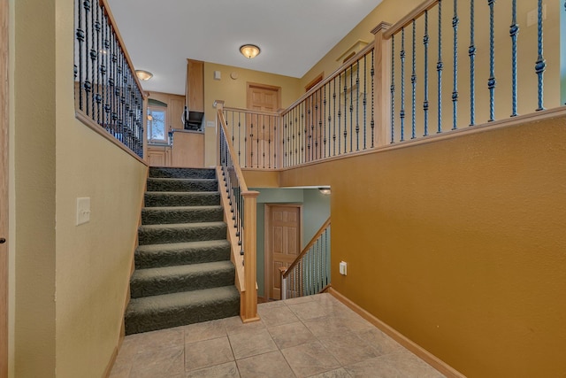 stairway with tile patterned floors and baseboards