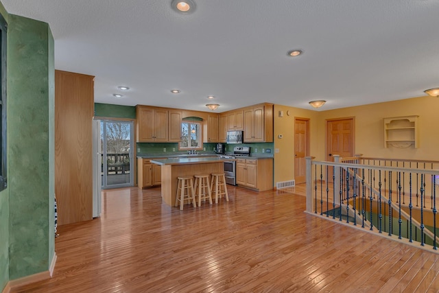 kitchen with light wood finished floors, visible vents, a kitchen island, and stainless steel appliances