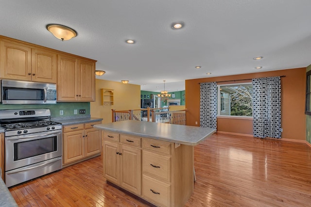 kitchen with a chandelier, stainless steel appliances, a center island, light brown cabinetry, and light wood finished floors