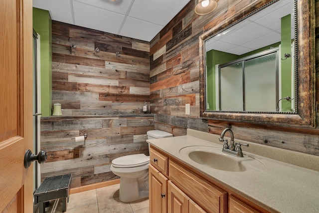 full bathroom featuring wood walls, toilet, a paneled ceiling, and a stall shower