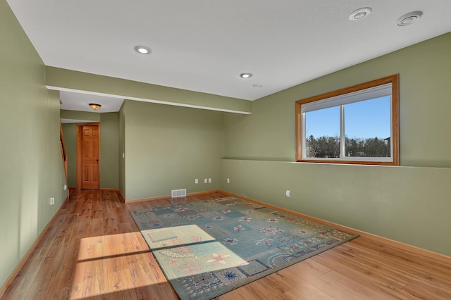 unfurnished room featuring baseboards, visible vents, and wood finished floors