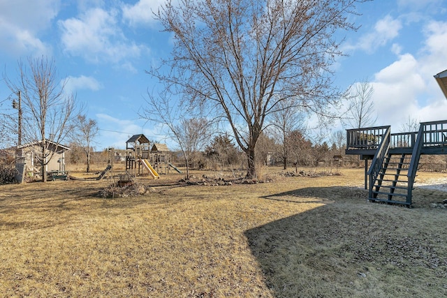view of yard with stairway, a wooden deck, and a playground