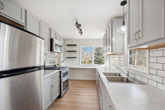 kitchen with light countertops, decorative light fixtures, open shelves, light wood-type flooring, and appliances with stainless steel finishes
