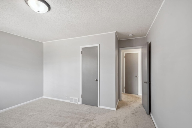 carpeted spare room with a textured ceiling, visible vents, crown molding, and baseboards