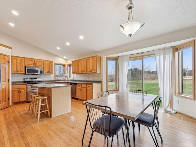 22184 Iman St NW, Nowthen, MN 55330 - kitchen featuring appliances with stainless steel finishes, a kitchen island, dark countertops, recessed lighting, and lofted ceiling