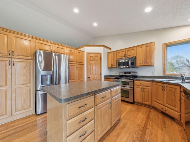 22184 Iman St NW, Nowthen, MN 55330 - kitchen with stainless steel appliances, a sink, lofted ceiling, dark countertops, and light wood-style flooring