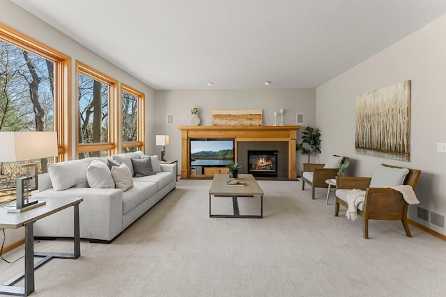 living area with light carpet, a tile fireplace, baseboards, and visible vents