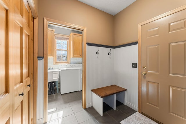mudroom featuring washer and dryer, light tile patterned flooring, baseboards, and a wainscoted wall