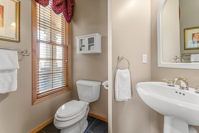 half bath with a sink, toilet, tile patterned flooring, and baseboards