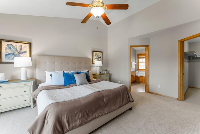 bedroom with ensuite bathroom, light carpet, a walk in closet, lofted ceiling, and baseboards