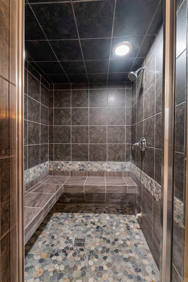 full bathroom featuring recessed lighting, tiled shower, and stone finish floor