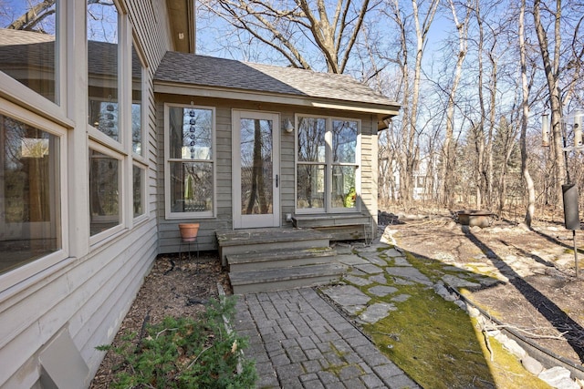 view of exterior entry with a shingled roof