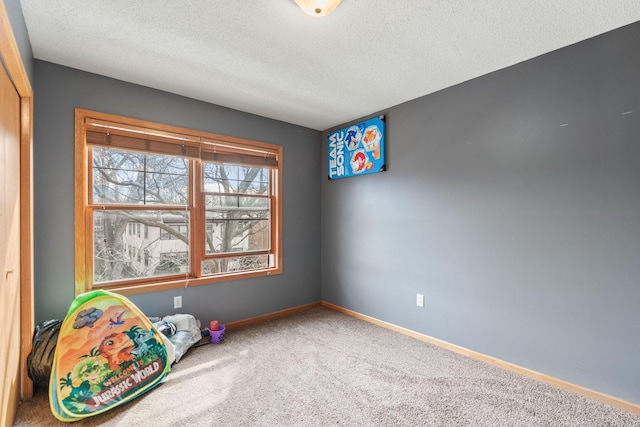 playroom featuring baseboards, carpet floors, and a textured ceiling