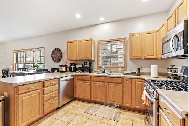 kitchen featuring light countertops, a sink, a peninsula, stainless steel appliances, and visible vents