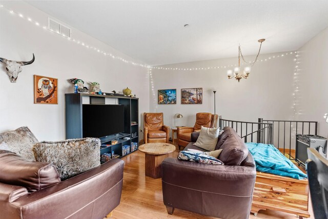 living room with visible vents, a chandelier, and light wood finished floors