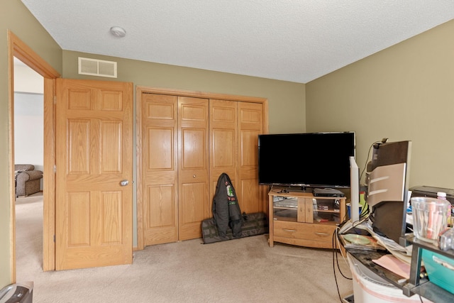 interior space featuring light carpet, visible vents, and a textured ceiling
