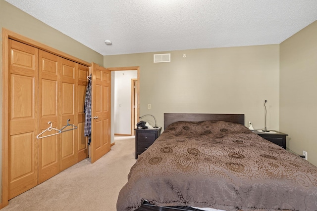 bedroom featuring a textured ceiling, a closet, light colored carpet, and visible vents