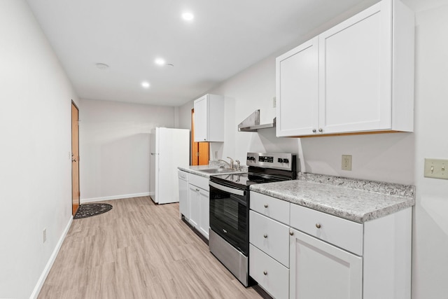 kitchen featuring white cabinets, wall chimney range hood, light countertops, and white appliances