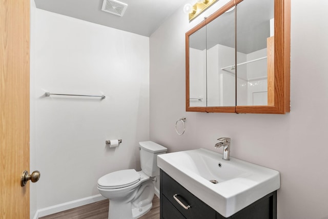 bathroom featuring visible vents, baseboards, toilet, wood finished floors, and vanity