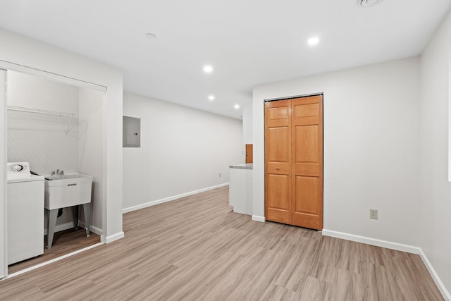 unfurnished bedroom featuring electric panel, washer / clothes dryer, baseboards, light wood-style floors, and recessed lighting